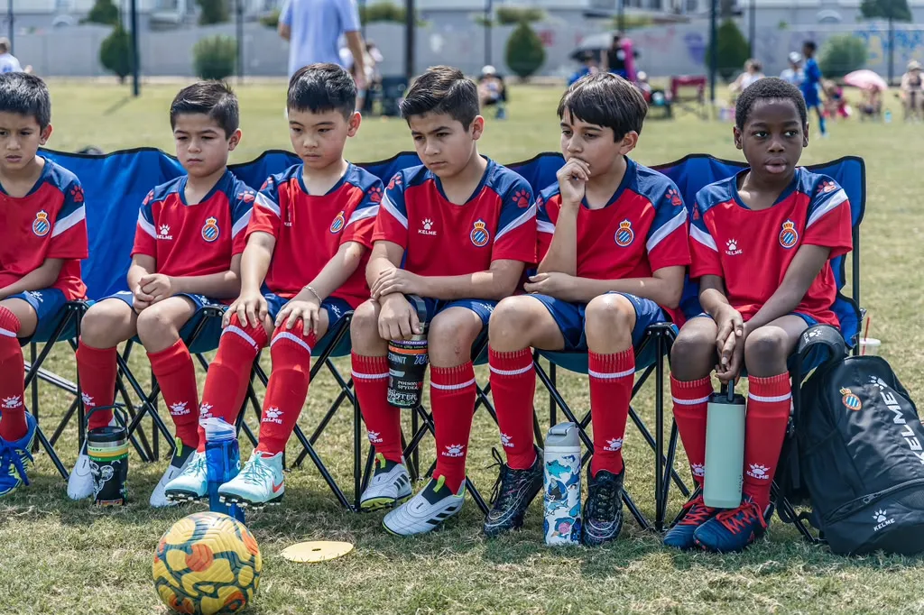 Squad seated on bench watching the match