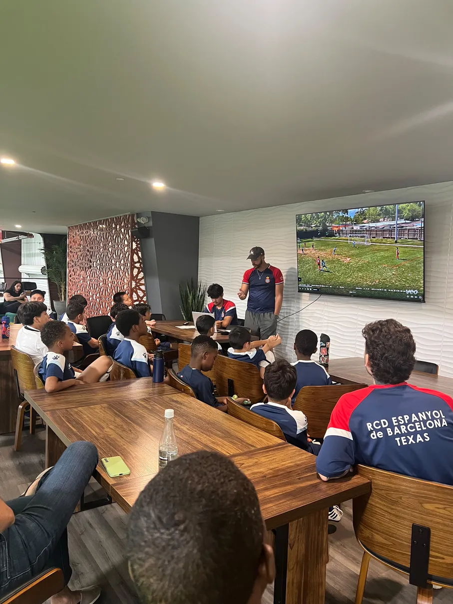 Coach running video analysis session with the academy squad in the team lounge